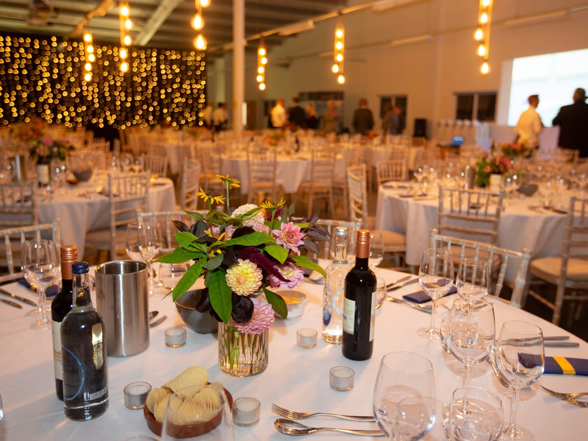 Elegant banquet setup with floral centrepieces, wine, and place settings at the 2021 Pendennis Apprentice Graduation ceremony.