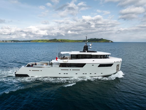 Explorer yacht FOX departs Falmouth, leaving a gentle wake behind, with coastal hills in the distance. Photography by 3Deep.
