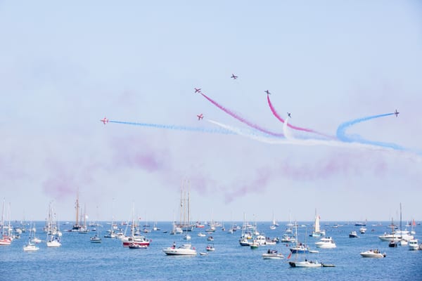Red Arrows flying in formation with coloured smoke trails over Falmouth Bay during the 2014 Pendennis Cup.