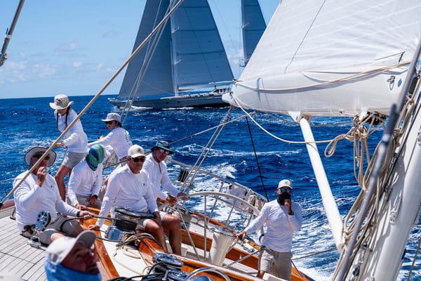 Onboard RebeccaCrew aboard a Rebecca in full concentration during a close race, with two modern yachts visible in the background.
