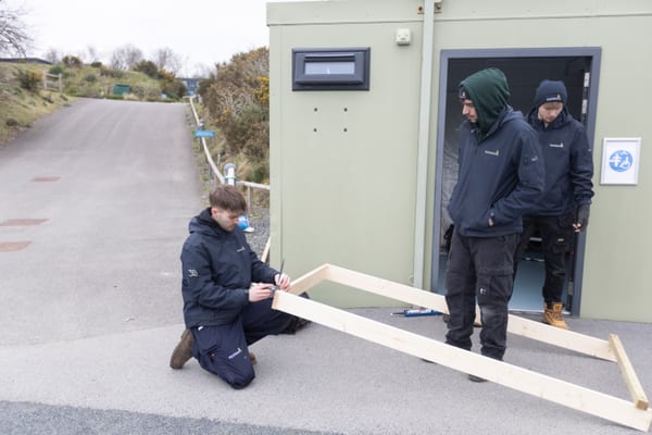Pendennis apprentice measuring timber with a colleague observing nearby.