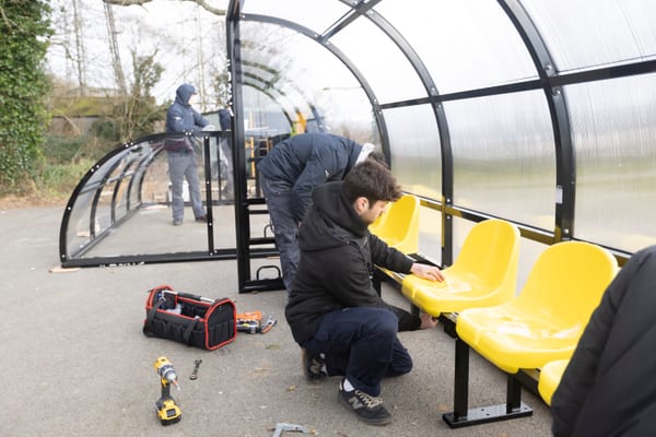 Pendennis apprentices assembling yellow seating inside a sports shelter.