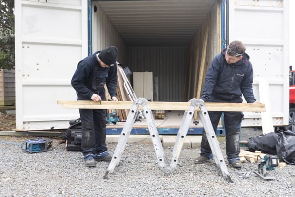 Pendennis apprentices marking timber on sawhorses outside a container unit.