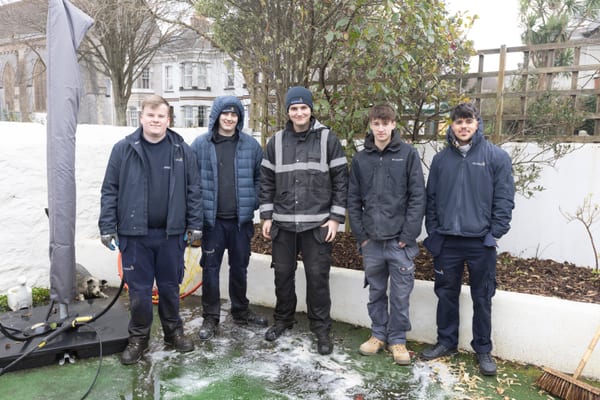 Group of Pendennis apprentices standing together in an outdoor courtyard area after completing a cleaning task.