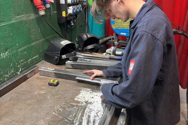 Pendennis apprentice preparing metal sections on a workbench in the welding area.