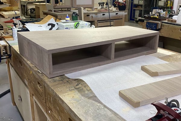 Completed wooden unit with two open compartments on a workbench in the Pendennis workshop.