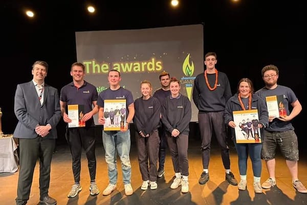 Pendennis apprentices holding certificates and posters on stage at the Cornwall College Apprentice Games awards.