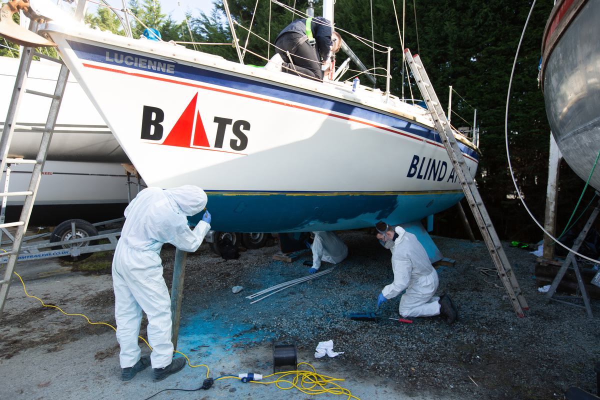 Apprentices cleaning and painting a boat