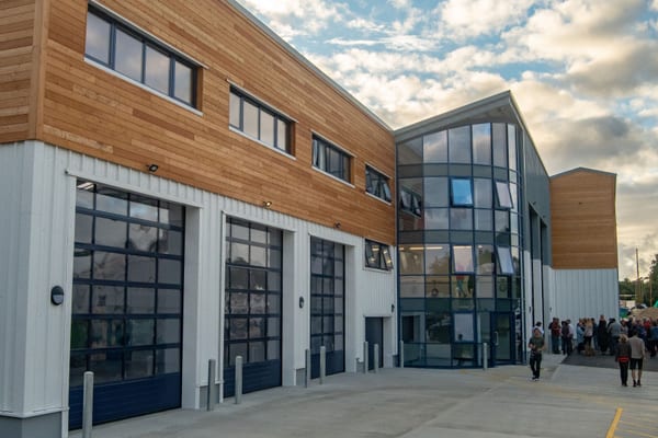 Exterior of the modern Cockwells Mylor HQ with timber cladding and large glass façade, during an open evening event.