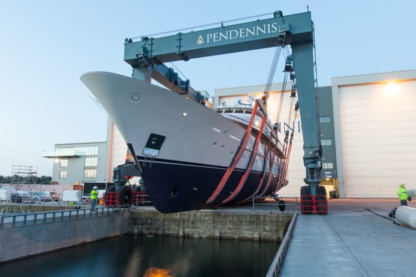 Superyacht Constance being lowered into the water at Pendennis Shipyard using a large mobile hoist.