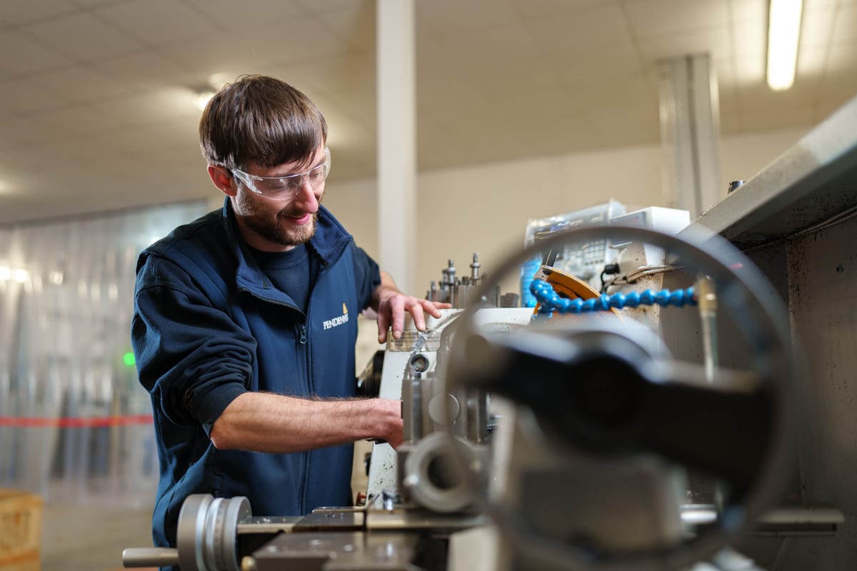 Engineer operating machinery at Pendennis’s Digital Manufacturing Centre, wearing safety goggles and uniform.