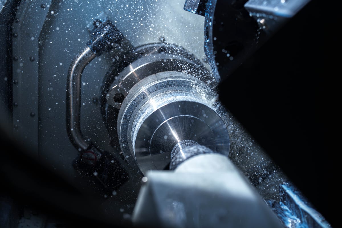 CNC machine cutting metal with coolant spray at Pendennis’s digital manufacturing centre.