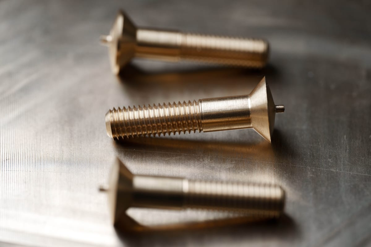 Close-up of precision-machined brass components on a metal workbench at Pendennis’s digital manufacturing facility.