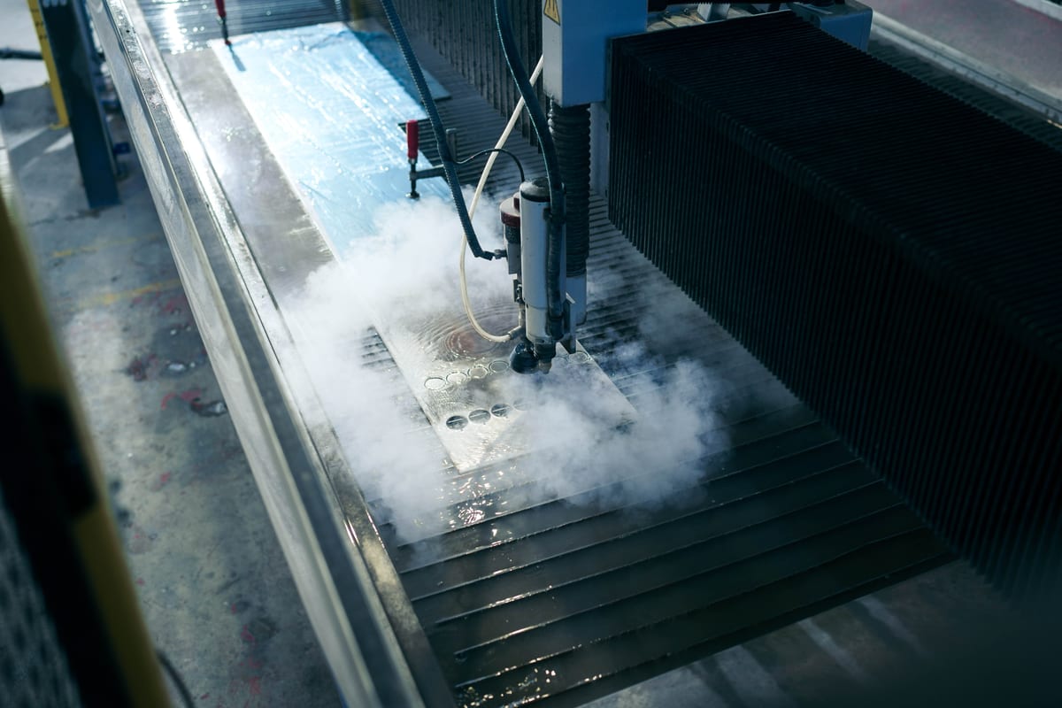 Close-up of a waterjet cutting machine producing metal components at Pendennis’s digital manufacturing centre.