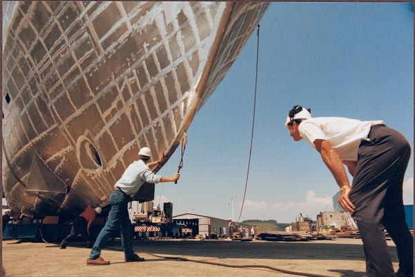 Shipbuilders guide the unfinished aluminium hull of Ilona during construction at Pendennis.