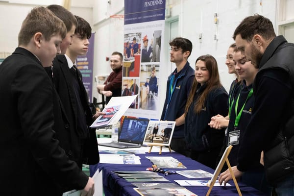 Pendennis apprentices engaging students at Redruth School’s Aspiration Fair, with displays promoting engineering careers.