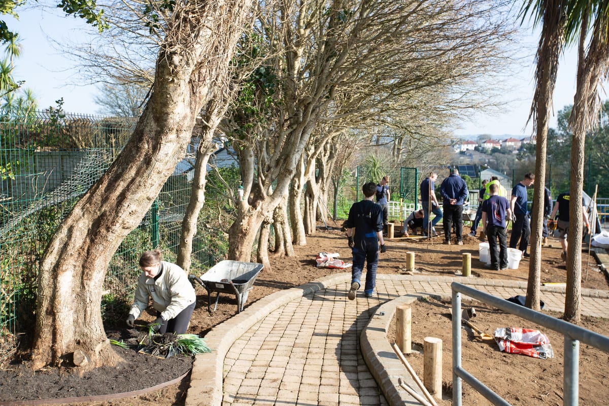 Pendennis apprentices and staff landscaping a sensory garden at St Mary’s School, laying paths and planting greenery.