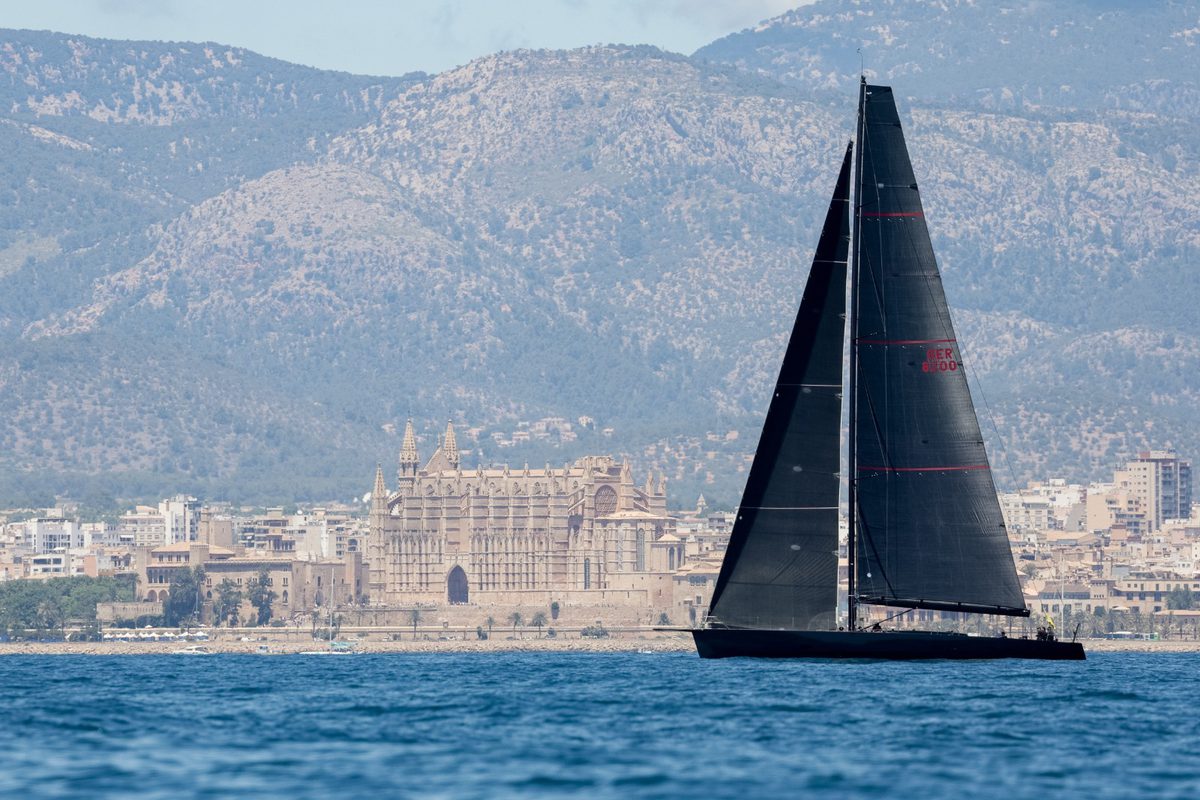 A black-sailed yacht passes in front of Palma’s cathedral during the Superyacht Cup Palma.