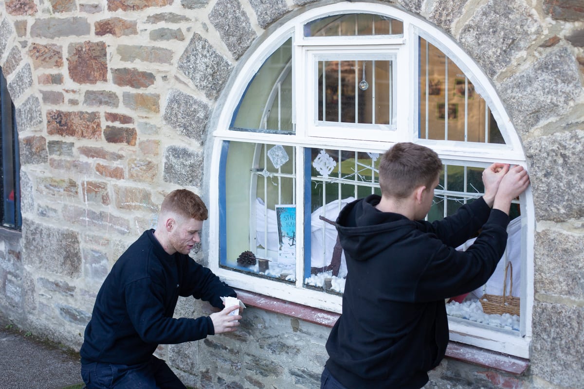 Pendennis paint apprentices working on the restoration of a window frame at The Crypt Pre-School.