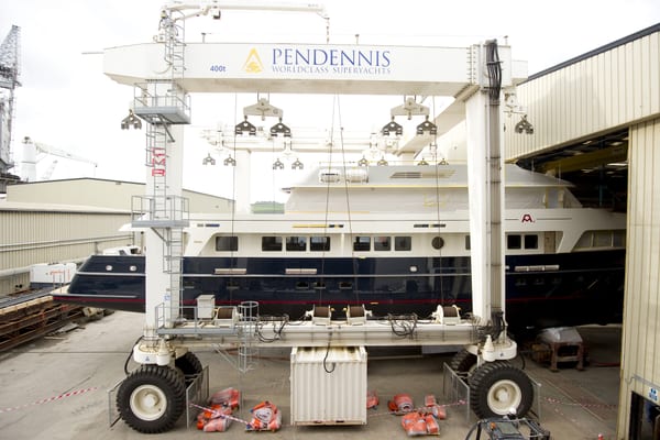 Motor yacht A2 during her refit at Pendennis Shipyard, positioned under the 400-ton travel hoist, partially wrapped and ready for works in the facility.