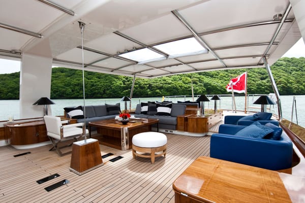 Akalam’s elegant aft deck in daylight, offering generous seating areas with polished wood details and panoramic waterfront views.