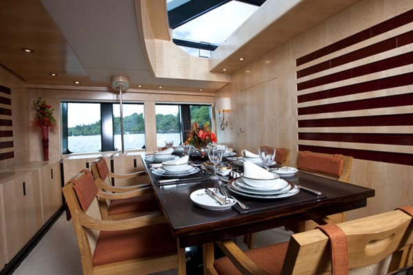 Akalam’s dining area, showcasing a sleek modern interior with natural light, panoramic windows, and a polished dark wood dining table set for guests.
