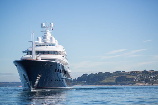 Superyacht Aquila departing from Pendennis, viewed from the bow with a coastal backdrop.