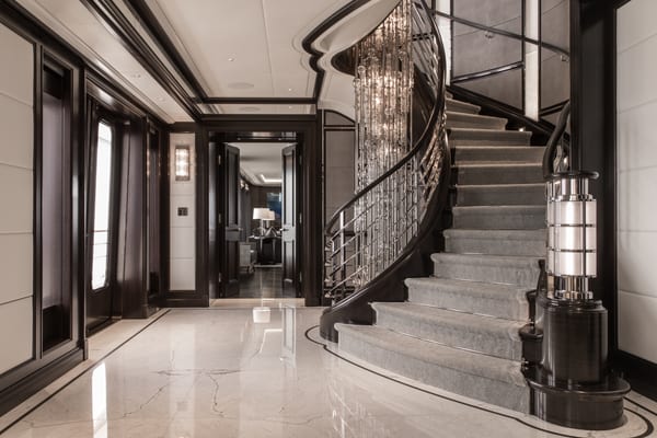 Aquila superyacht’s grand staircase featuring an 11-metre chandelier made up of over 850 glass pieces cascading through four deck levels.