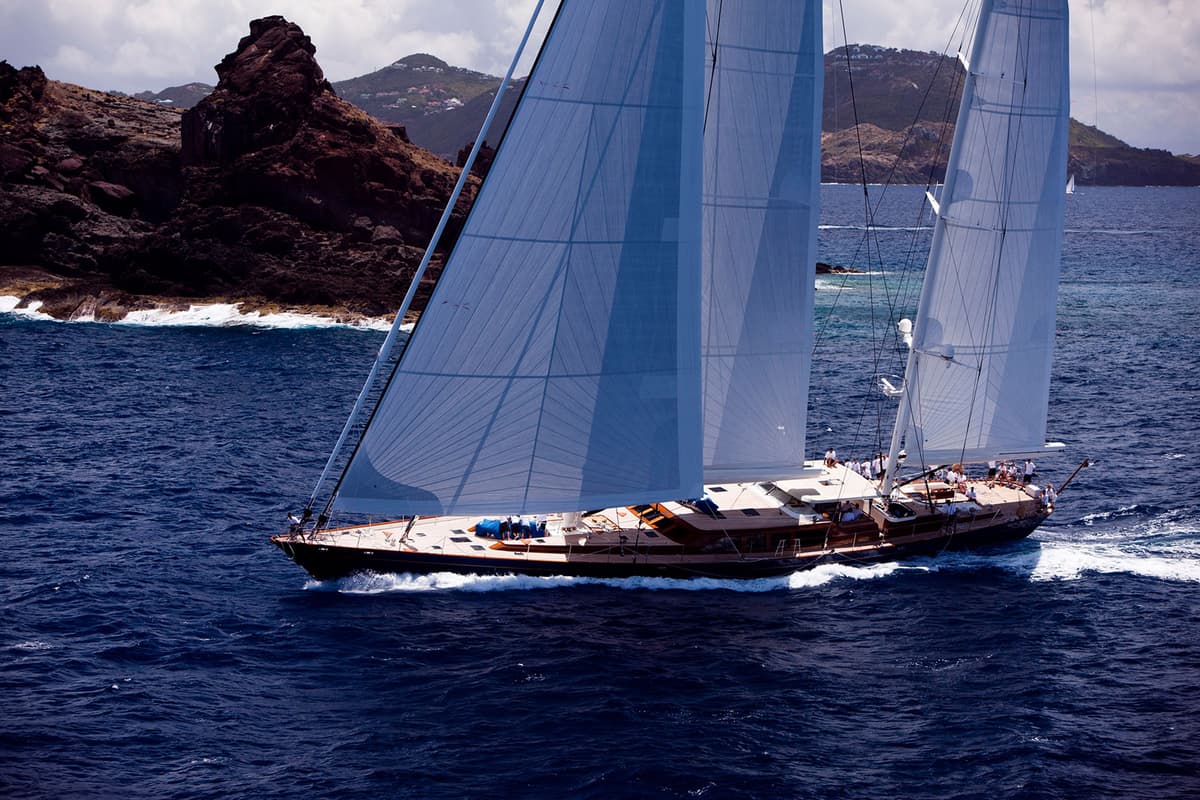 Christopher sailing past rugged coastlines with its sails up, cutting through the blue water on a sunny day at the St Barths Bucket in 2011.