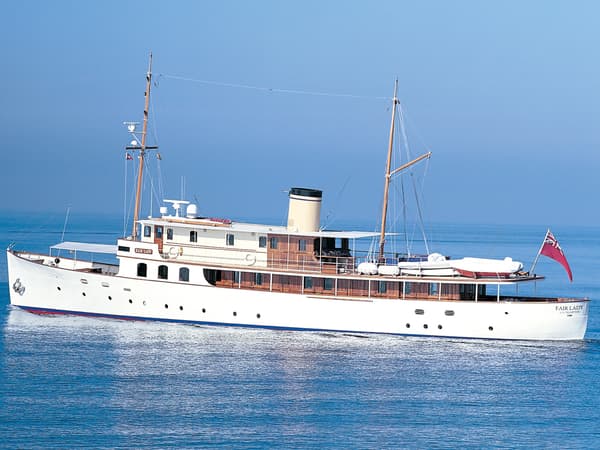 Classic motor yacht Fair Lady cruising on calm seas under clear blue skies after restoration.