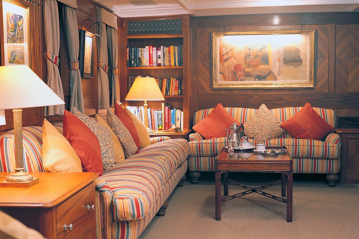 Cosy lounge area on motor yacht Fair Lady following her extensive 1996 refit at Pendennis, featuring striped upholstery and wood paneling.