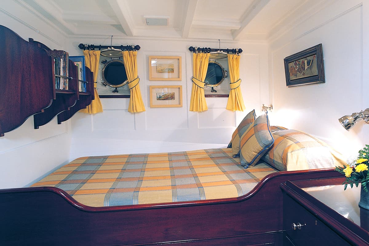 Guest cabin on motor yacht Fair Lady following her extensive 1996 refit at Pendennis, featuring wood details and porthole windows.