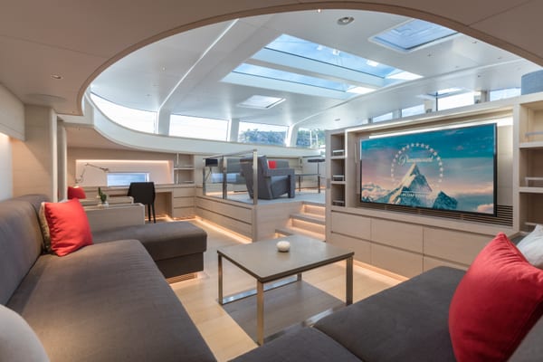 Main saloon on superyacht G2 with large skylights, sunken lounge area, and integrated cinema screen.
