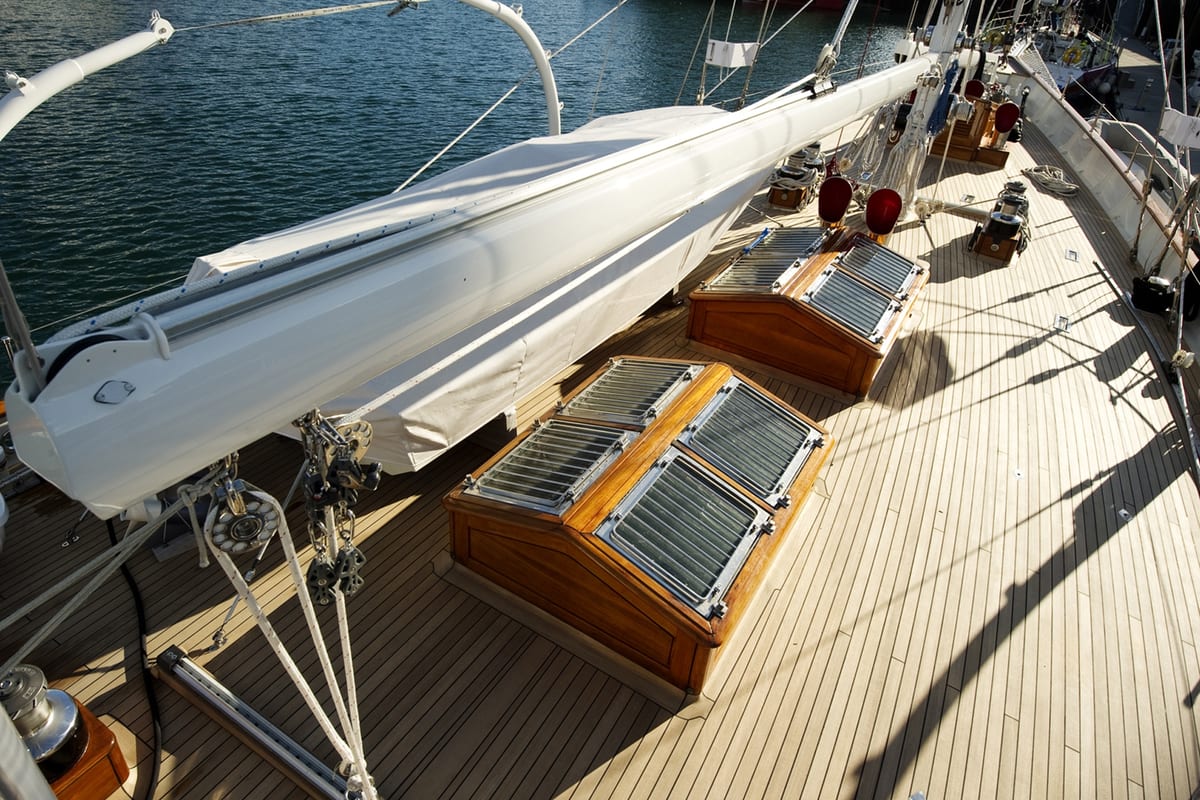 Teak deck of sailing yacht Gloria showing varnished skylights, winches and sail handling equipment.
