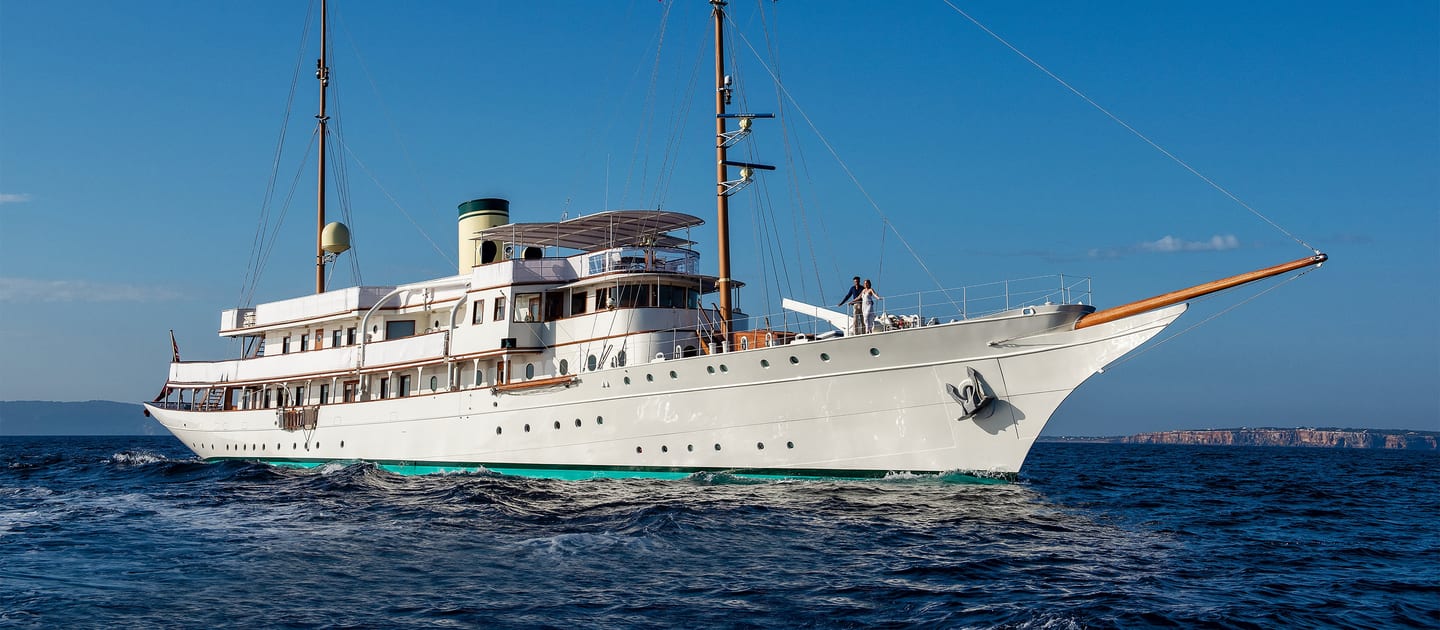 Classic superyacht Haida 1929 cruising at sea after restoration, under clear blue skies.