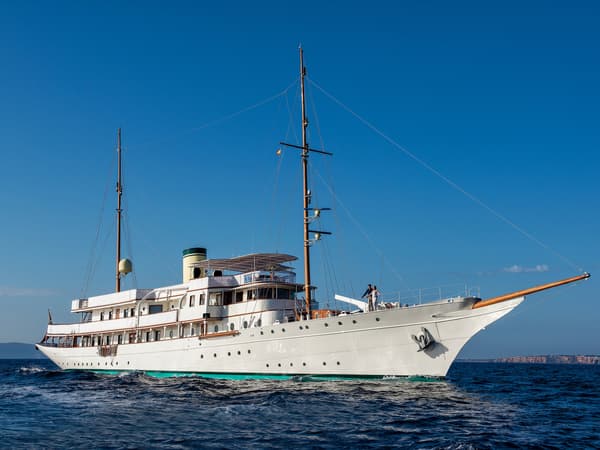 Classic superyacht Haida 1929 cruising at sea after restoration, under clear blue skies.