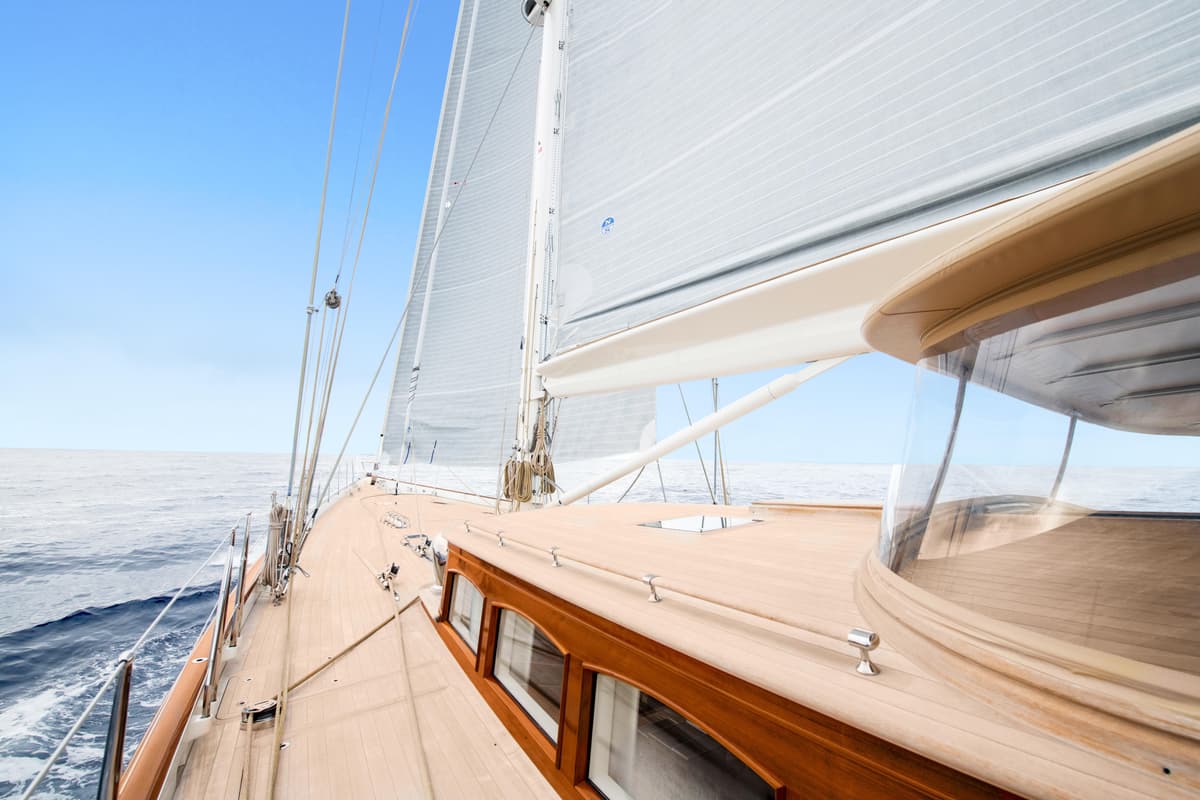View along Halekai's teak deck under sail, showing sleek lines, timber cabin detailing, and ocean horizon.