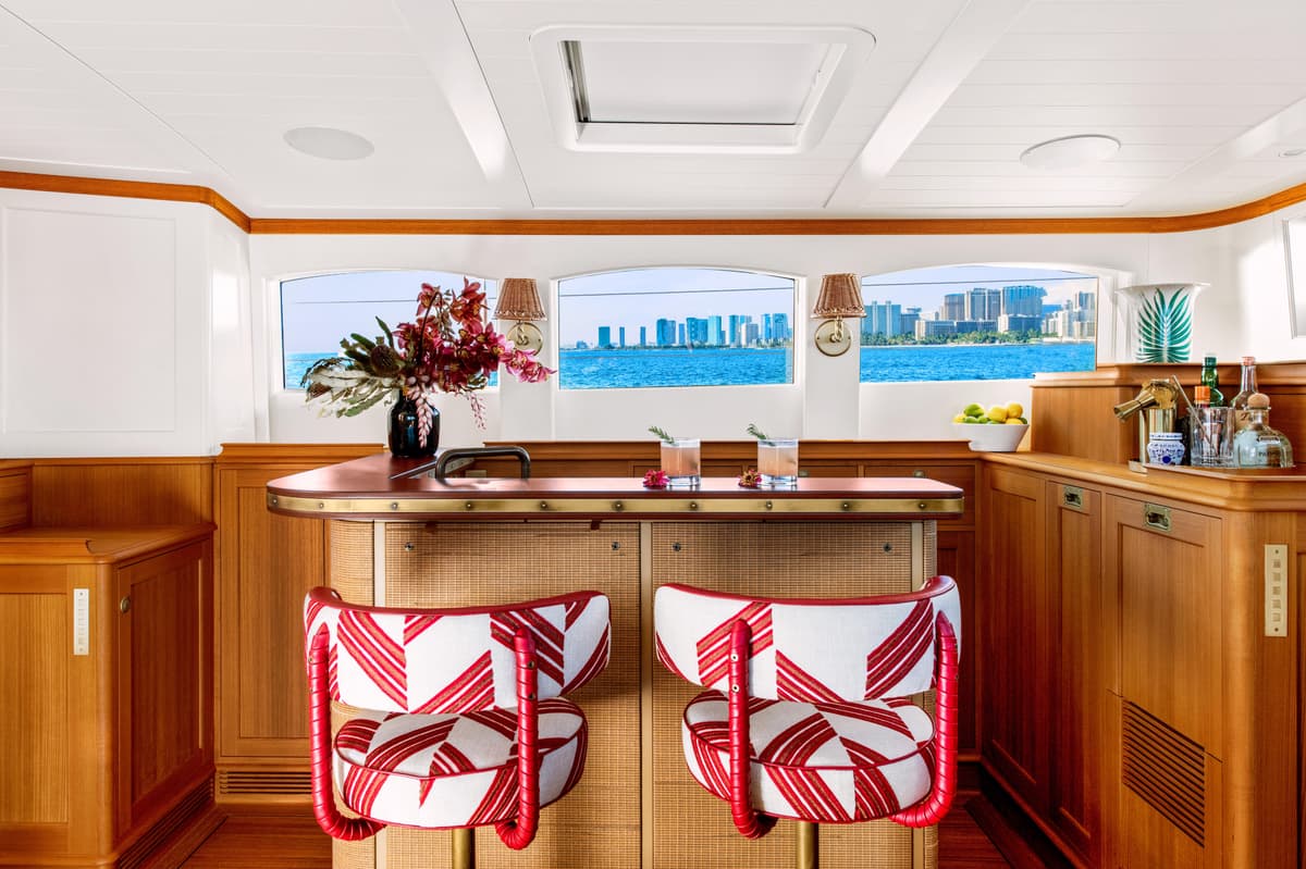 Halekai’s indoor bar with red patterned stools, tropical flowers, and ocean views of Honolulu skyline.