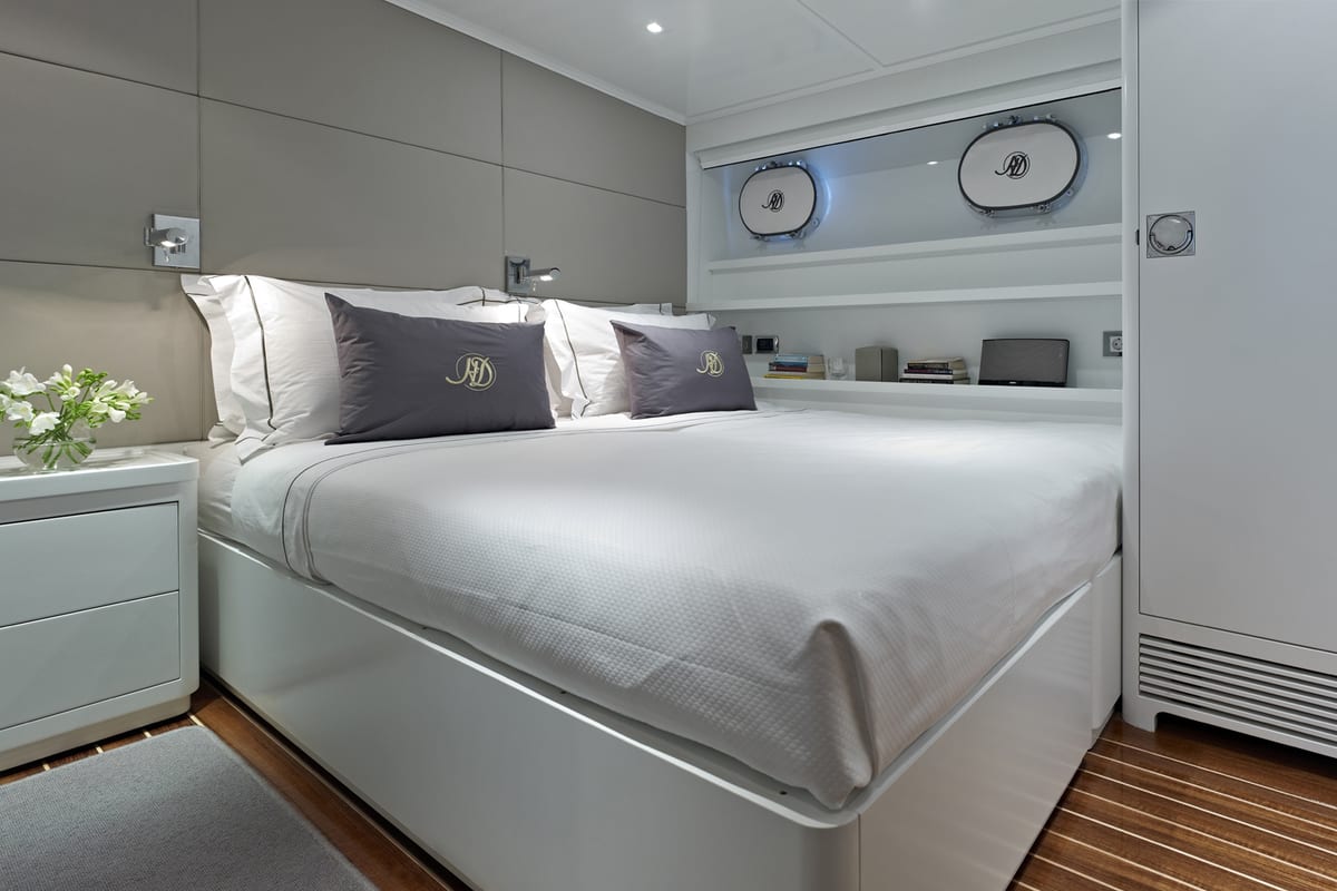 Contemporary double guest cabin on Heavenly Daze with monogrammed pillows, portholes, and sleek white interiors.