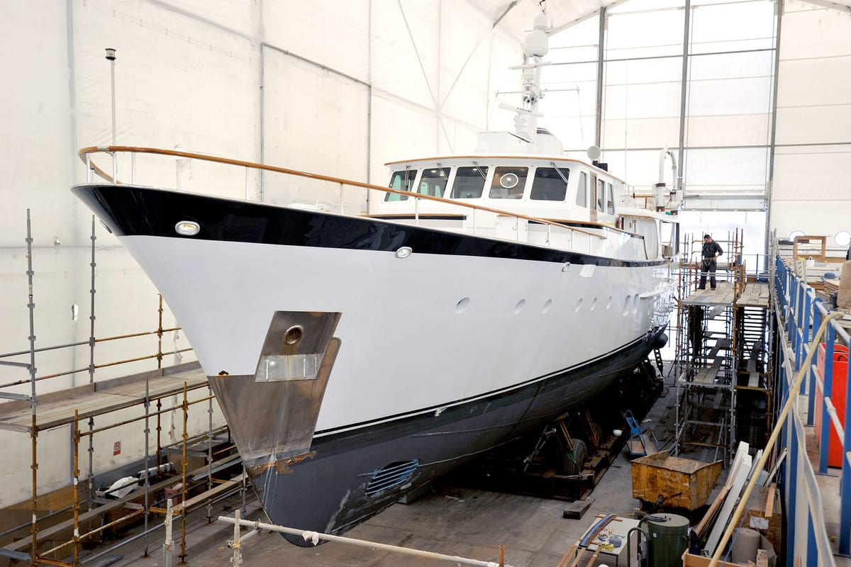Classic motor yacht Heavenly Daze in a covered dry dock at Pendennis, surrounded by scaffolding during refit works.