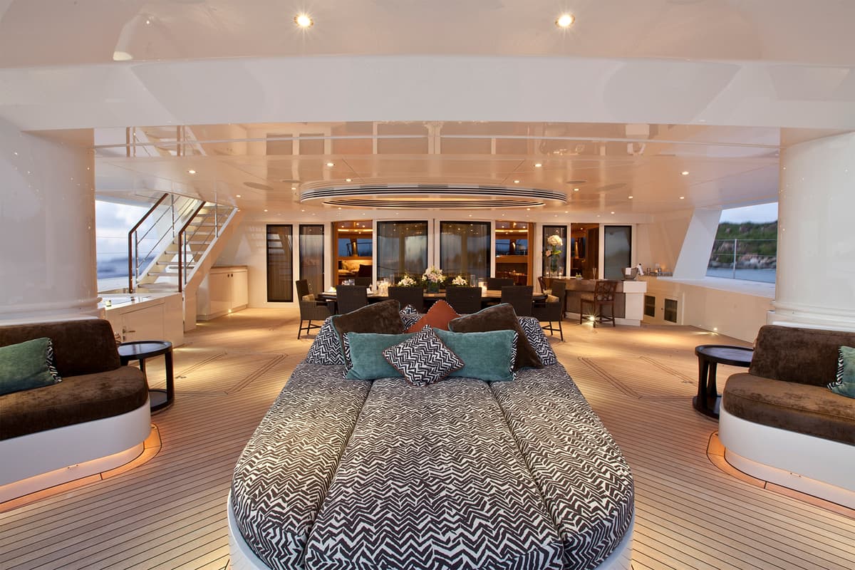 Stylish outdoor lounging and dining area on Hemisphere’s aft deck with patterned cushions and soft evening lighting.