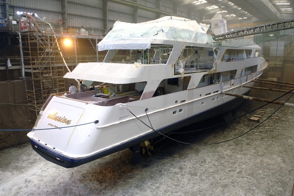 Superyacht Illusion in Pendennis’ dry dock during flood up after an eight-month refit, with crew working on deck.