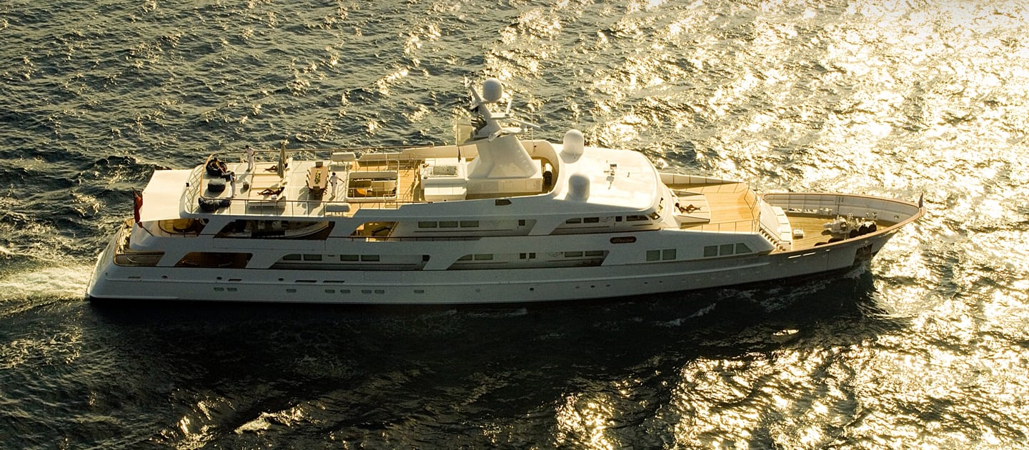 Aerial view of superyacht Illusion cruising through golden, sunlit waters after refit.