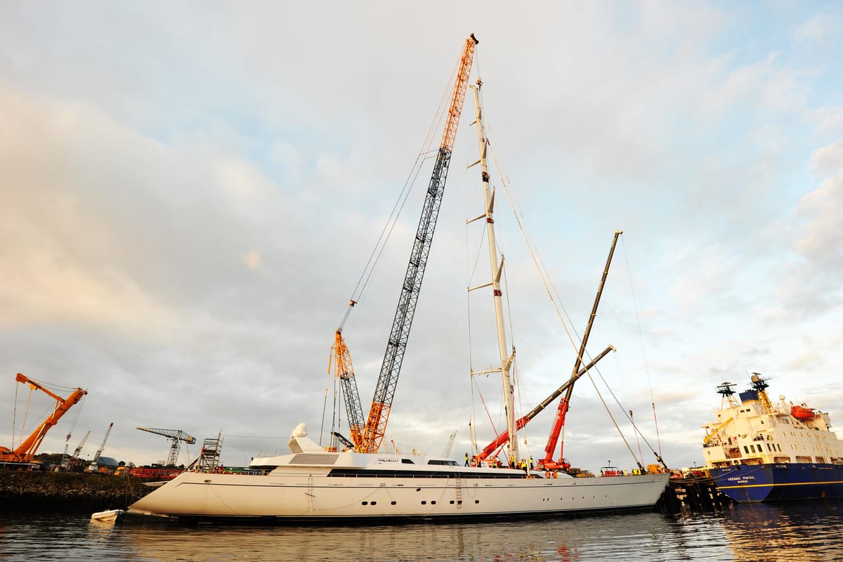 Three cranes working to de-mast the superyacht Mirabella V at Pendennis during refit operations.