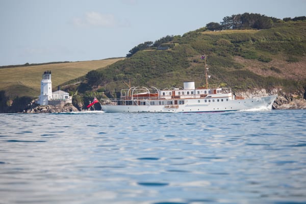 Restored classic motor yacht Malahne cruising past St Anthony lighthouse during sea trials in Falmouth Bay.