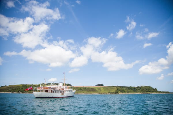 Classic motor yacht Malahne underway in calm waters off the Cornish coast under blue summer skies.