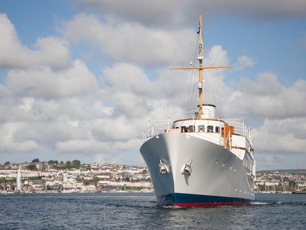 Classic motor yacht Malahne returning to Falmouth Harbour with the town visible in the background.