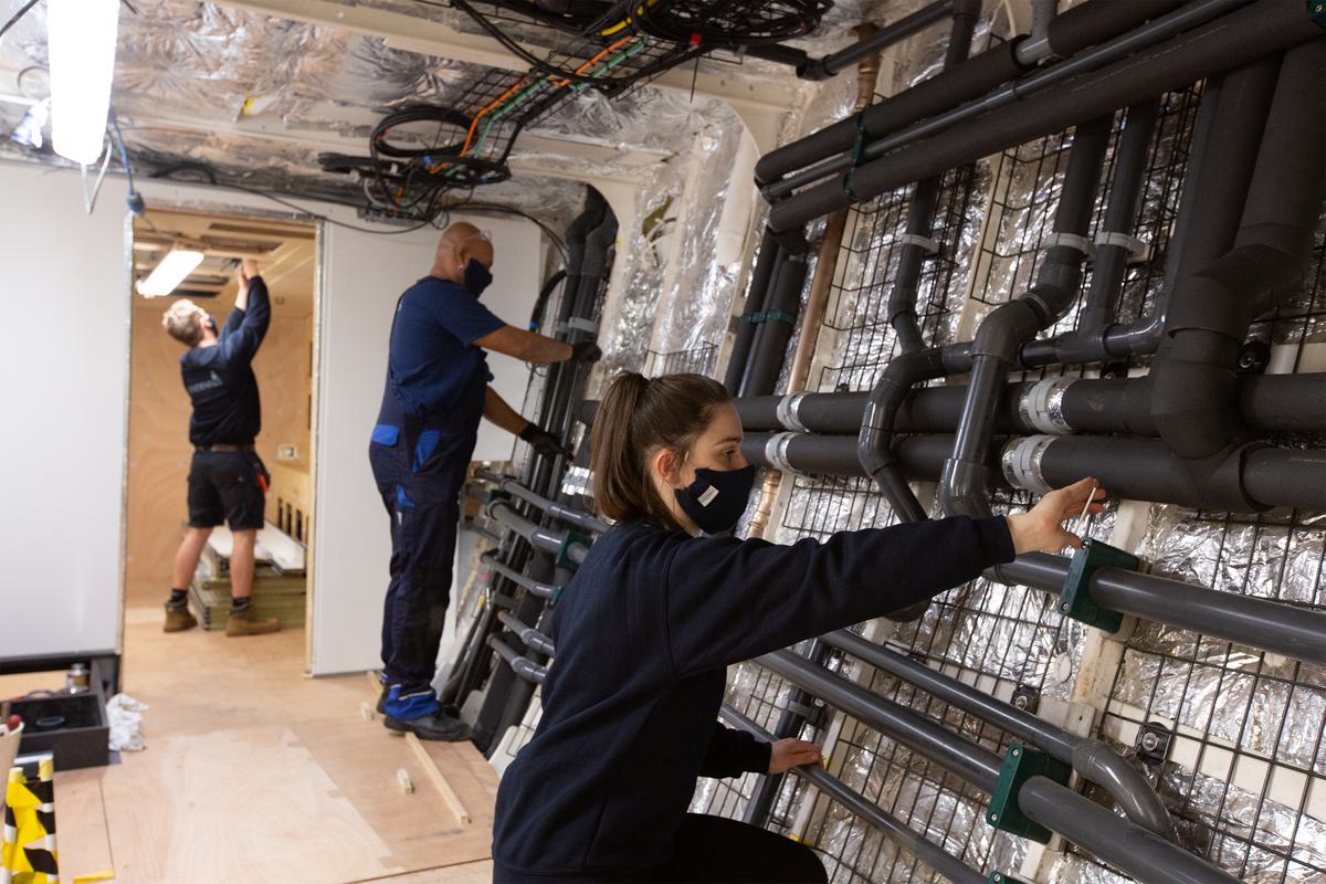 Three staff members working on plumbing and electrics