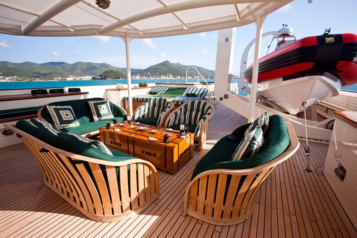 Aft deck of explorer yacht STEEL featuring a shaded seating area with green cushions and tender stored on deck.