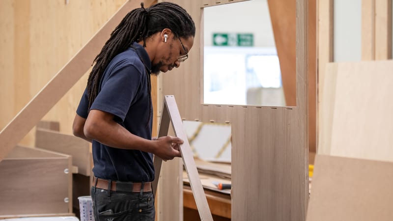 Norfolk Interiors team member inspecting a timber frame in a precision joinery workshop.